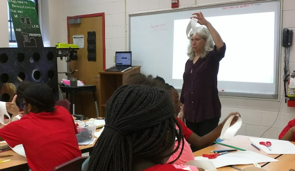 Teacher demonstrating a Möbius strip to engaged classroom students